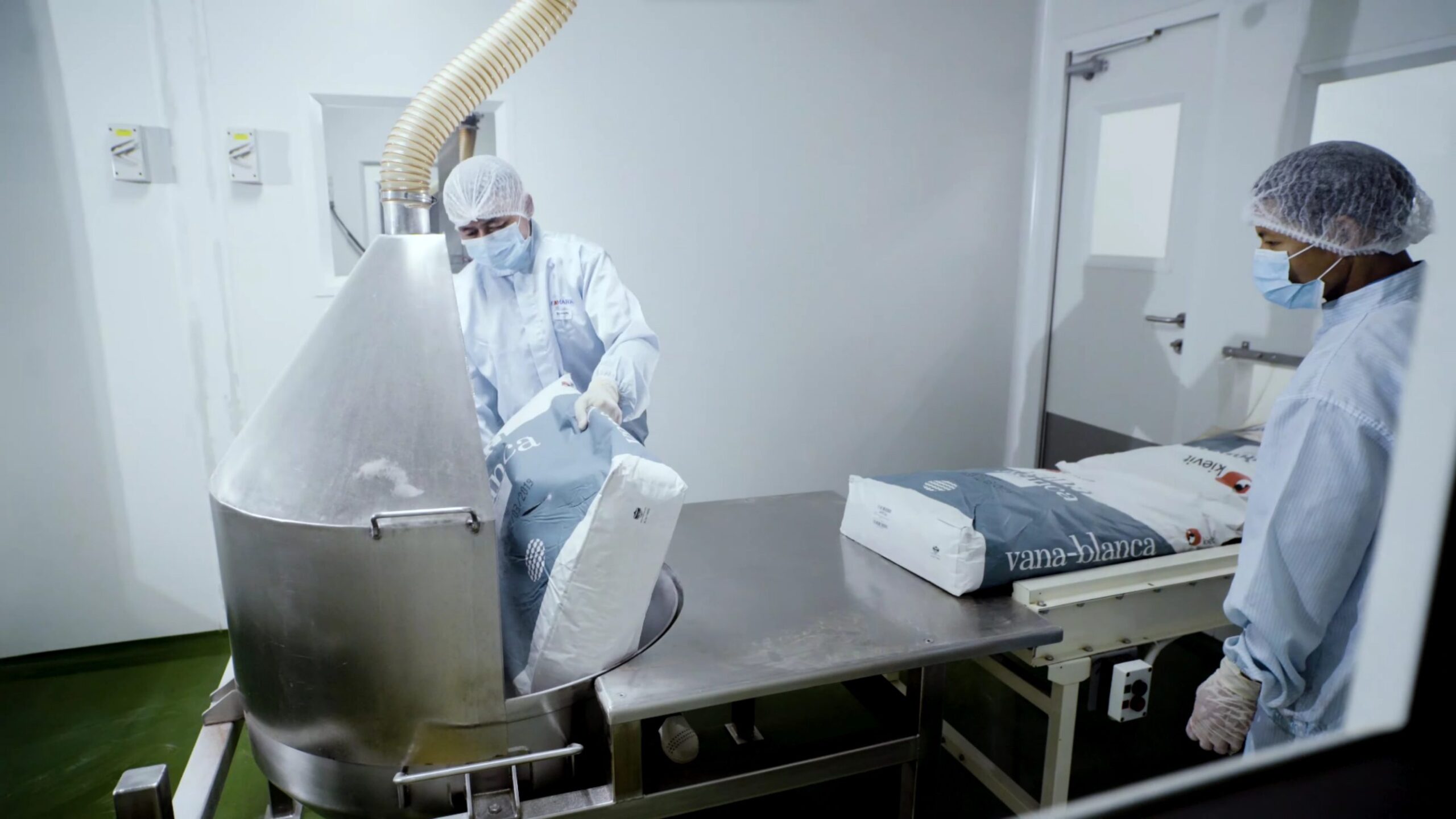 Operator loading material into a stainless steel vessel in the cleanroom