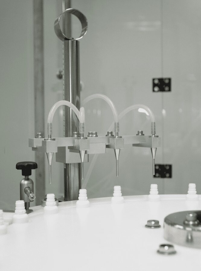 Filling nozzles dosing liquid into white bottles