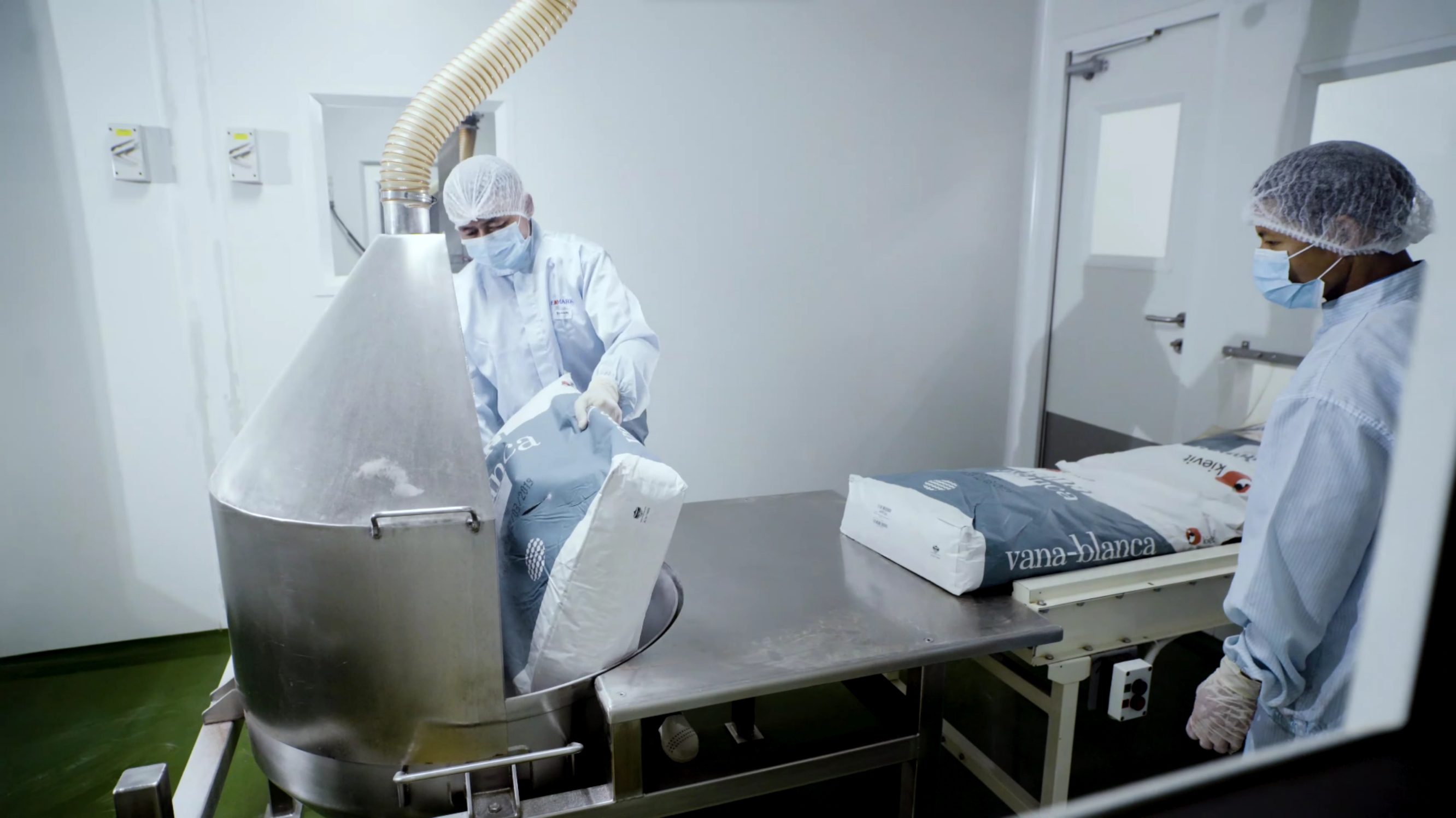 Operator loading material into a stainless steel vessel in the cleanroom