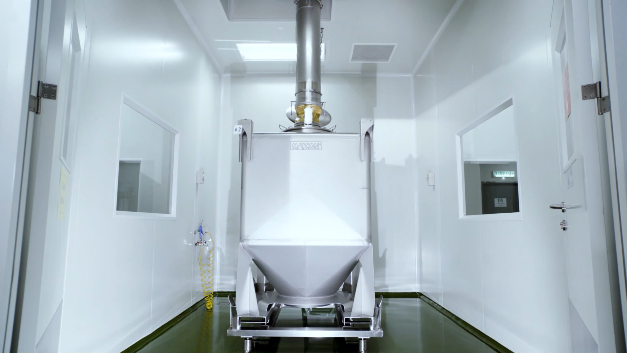 Gravity discharge hopper feeding product between cleanroom floors
