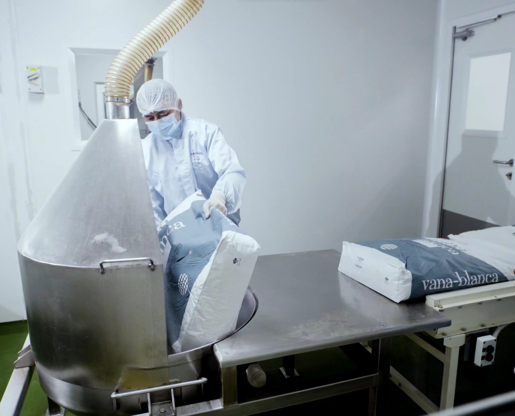 Operator loading material into a stainless steel vessel in the cleanroom