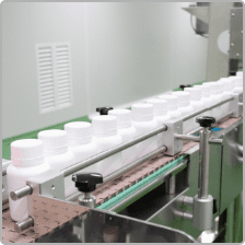 White HDPE bottles moving along the capping and labelling conveyor