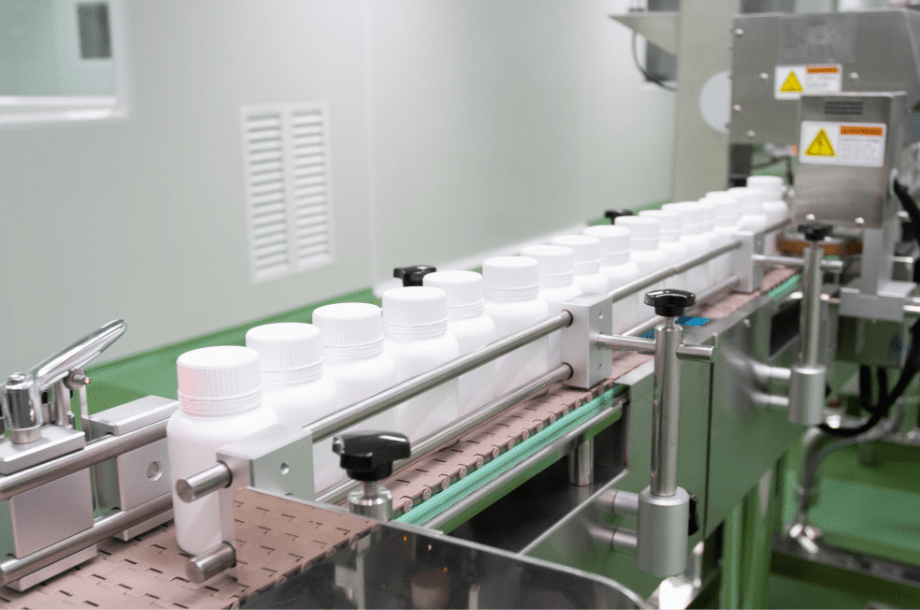 White HDPE bottles moving along the capping and labelling conveyor