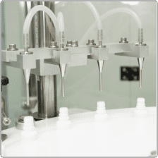 Filling nozzles dosing product into white bottles in D Block