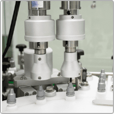 Automatic capping heads sealing bottles on the D Block line