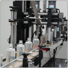 Capping and labelling station for clear bottles
