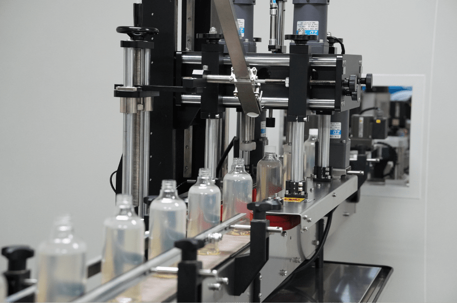 Capping and labelling station for clear bottles