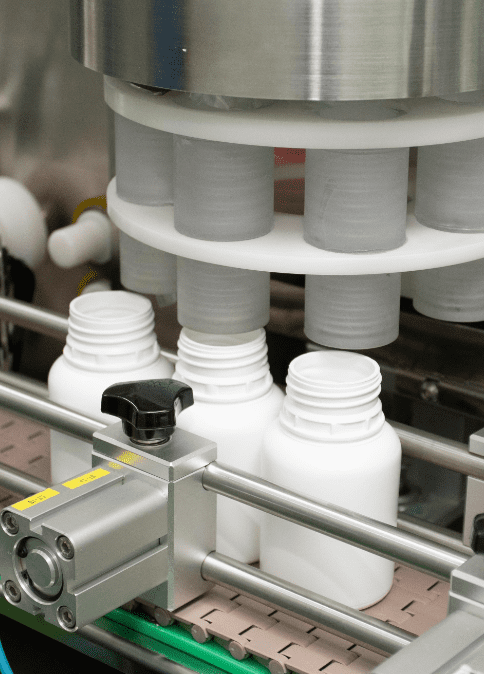 White HDPE bottles passing through the automatic capping unit