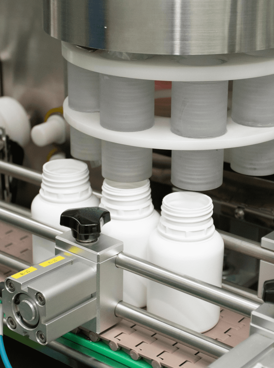 White HDPE bottles passing through the automatic capping unit