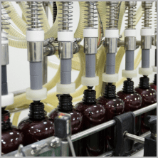 Filling nozzles dosing traditional herbal liquid into amber bottles
