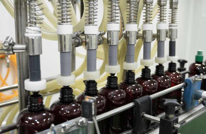 Filling nozzles dosing traditional herbal liquid into amber bottles