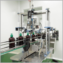 Amber bottles moving through the capping station on the traditional products line