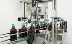 Amber bottles moving through the capping station on the traditional products line