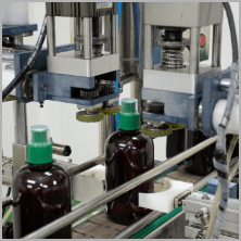 Automatic capping head sealing an amber bottle of herbal liquid