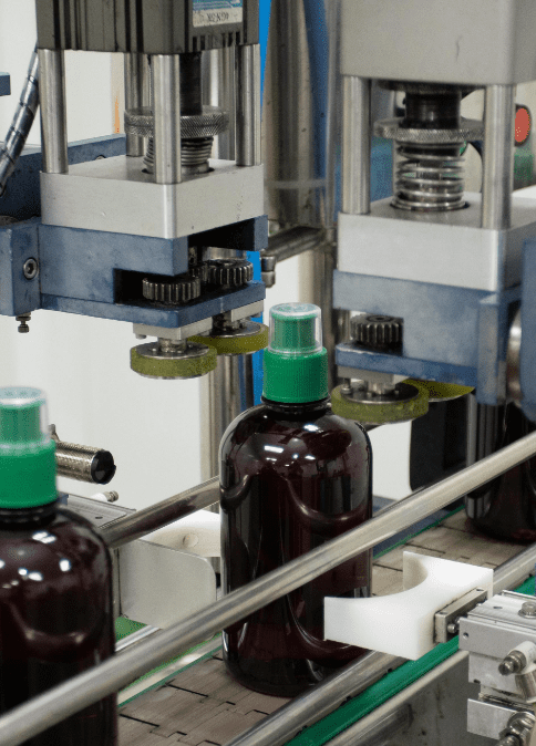 Automatic capping head sealing an amber bottle of herbal liquid