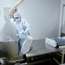 Operator loading material into a stainless steel vessel in the cleanroom