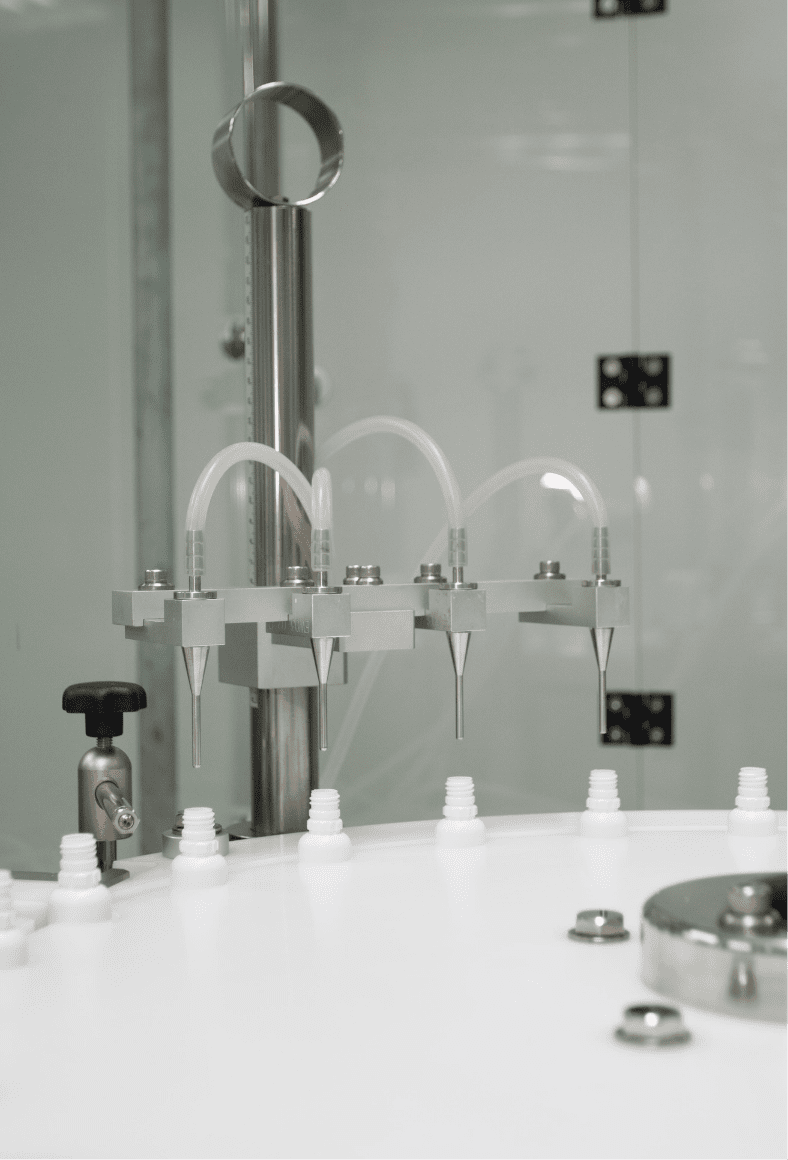 Filling nozzles dosing liquid into white bottles