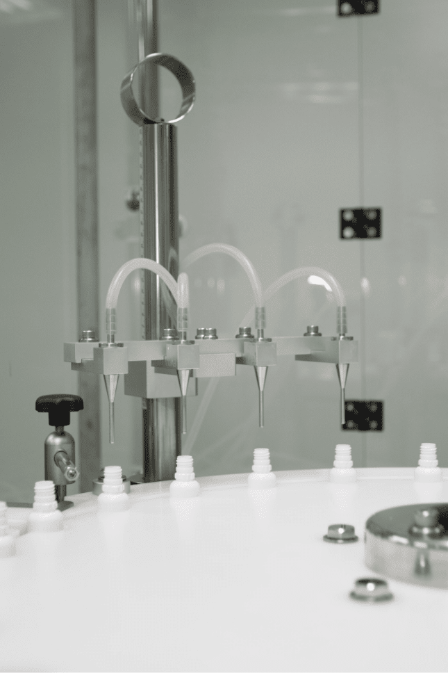 Filling nozzles dosing liquid into white bottles
