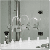 Filling nozzles dosing liquid into white bottles