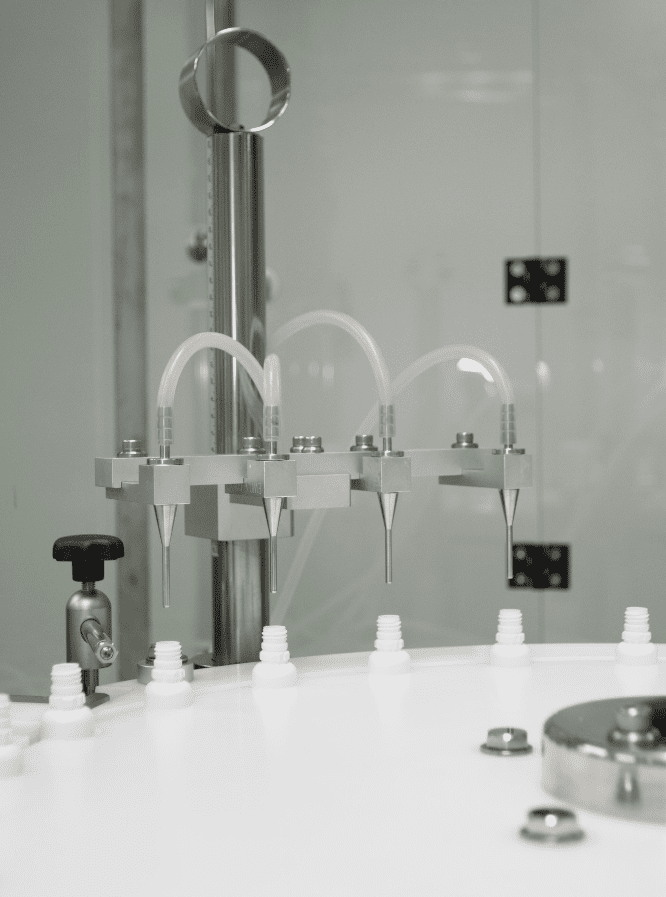 Filling nozzles dosing liquid into white bottles