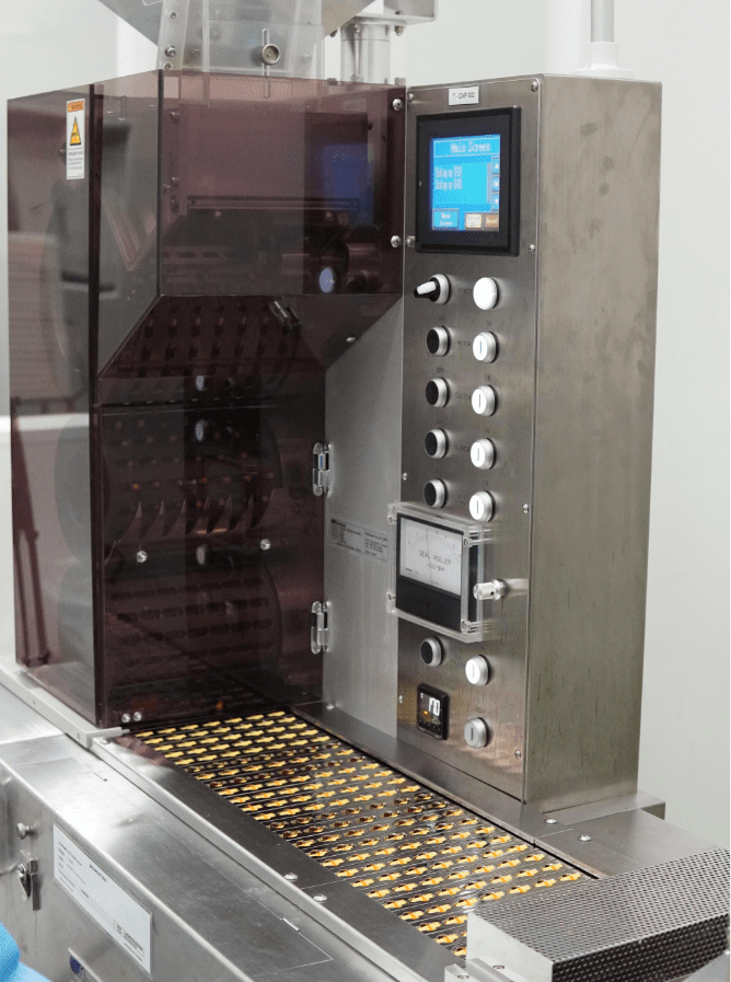 Softgel capsules in carrier trays inside the processing machine