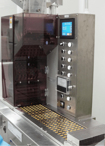 Softgel capsules in carrier trays inside the processing machine
