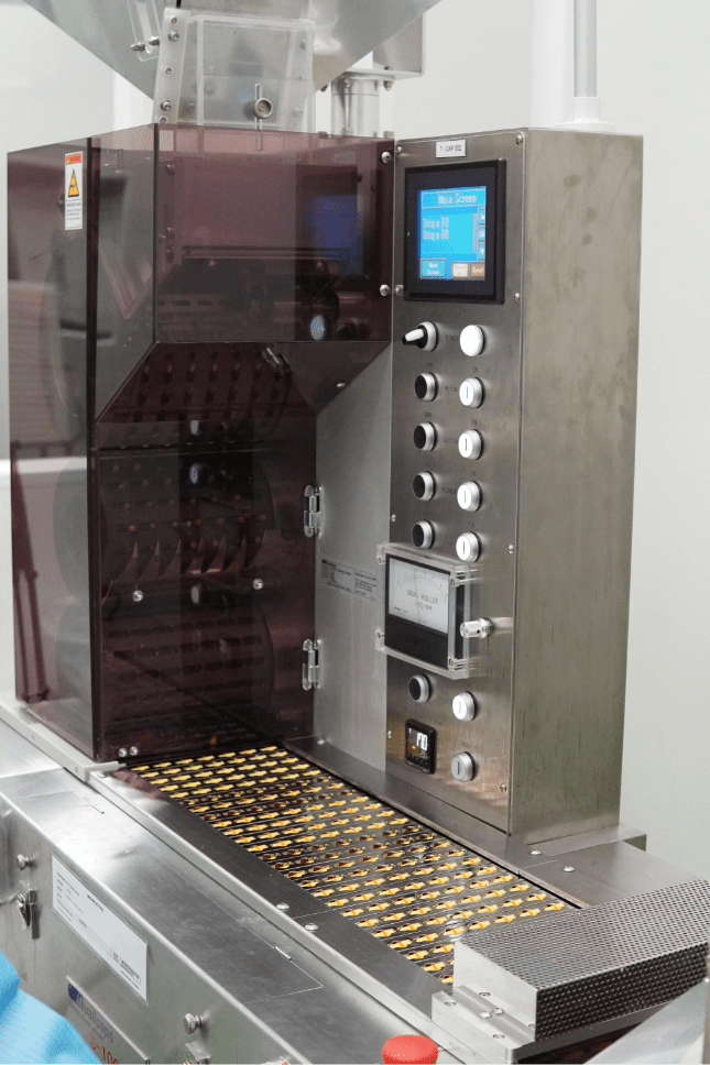 Softgel capsules in carrier trays inside the processing machine
